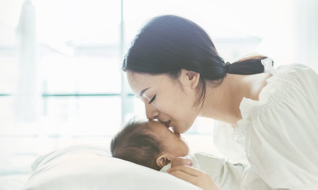 mom kissing newborn baby